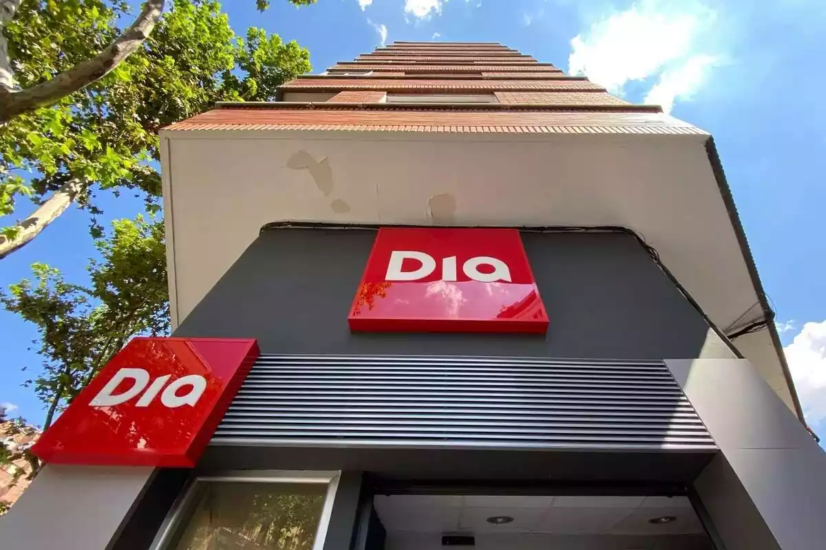 Entrada d´un supermercat Dia vista des de l´exterior, amb dos logos amb el fons vermell i les lletres blanques