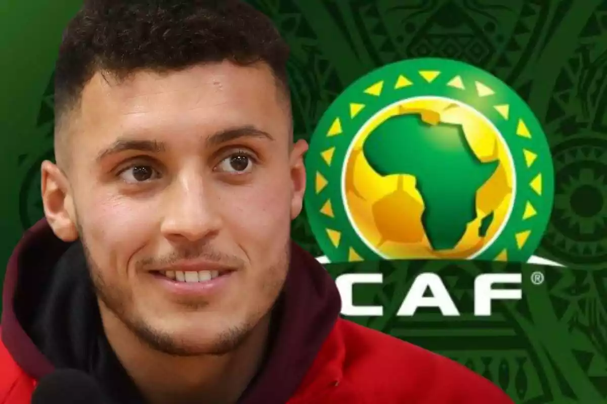 Selim Amallah amb un mig somriure davant del logo de la Copa Àfrica